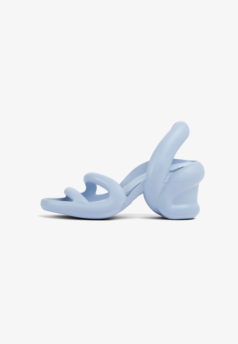 Light blue heeled sandals, made of smooth rubber, featuring a sculptural design with wavy straps and a chunky heel.