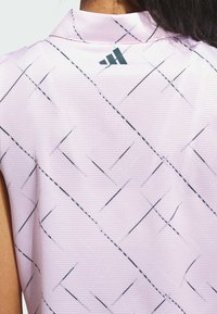 Ljusrosa polo skjorta med en randig struktur och ett svart diagonalt mönster. Inkluderar en liten logotyp vid kragen.
