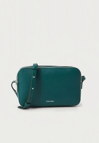 Žalsvai mėlynas stačiakampio formos odinis per petį nešiojamas krepšys su sidabriniu užtrauktuku, reguliuojamu dirželiu ir mažu Calvin Klein logotipu priekyje centre.