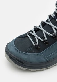 Scarpa da trekking blu scuro con upper in suede, mesh testurizzato, lacci grigi e accessori in plastica nera. Suola spessa e strutturata per una buona aderenza.