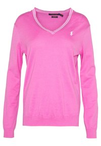 Růžový svetr s výstřihem do V a dlouhými rukávy, se spojenými manžetami a lemem. Obsahuje bílé pruhované akcenty kolem výstřihu a malé logo na hrudi.