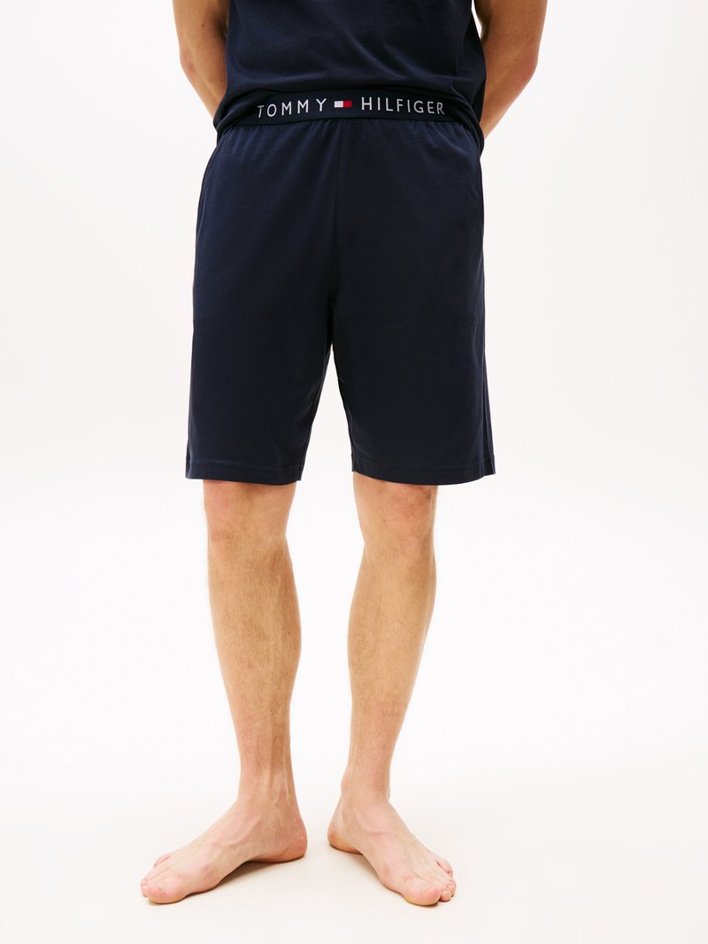 Mann, der marineblaue Tommy Hilfiger-Shorts trägt und von hinten zu sehen ist, barfuß steht er vor einem weißen Hintergrund.