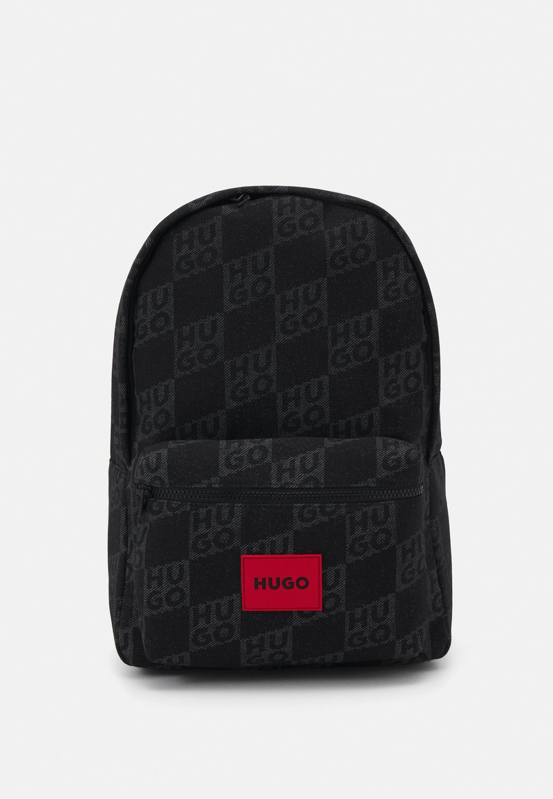 Zaino in tessuto nero con un motivo di logo sottile. Tasca frontale con zip e un prominente patch con logo rosso nella parte inferiore anteriore. Texture liscia.