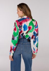 Kleurige blouse met lange mouwen met een aquarel bloemenpatroon in tinten groen, rood, blauw en zwart. Lichte, gladde stof.