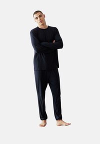 Černá dlouhá rukávová košile a odpovídající kalhoty, vyrobené z hladkého materiálu. Casual střih s uvolněným designem, bez viditelných vzorů nebo akcentů.