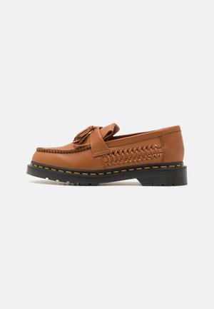 Mocassins en cuir marron avec des accents tressés et des glands, dotés d'une semelle noire avec des bords jaunes et d'un design à bout rond.