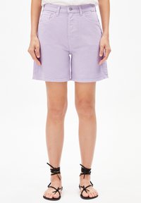 Světlé fialové deniminové kraťasy se jednoduchým designem, předními kapsami a zapínáním na knoflík, v kombinaci s černými sandály na řemínky.
