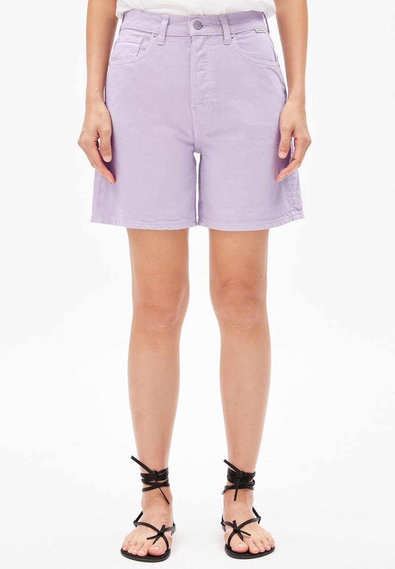 Světlé fialové deniminové kraťasy se jednoduchým designem, předními kapsami a zapínáním na knoflík, v kombinaci s černými sandály na řemínky.