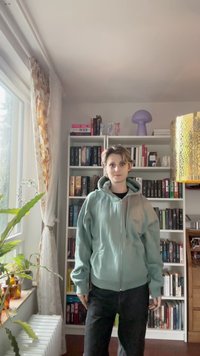 Mintgrønn zip-up hettegenser med avslappet passform, stor hette og sidelommer, kombinert med svarte bukser. Mykt, teksturert stoff.