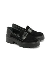 Czarne loafersy wykonane z zamszu i skóry, z masywną gumową podeszwą i ozdobnym paskiem z przodu. Gładka tekstura i zaokrąglony kształt.