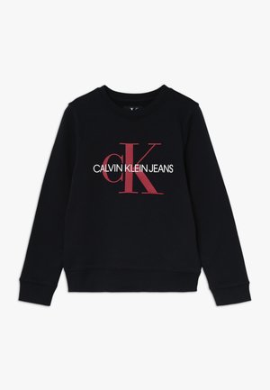Musta collegepaita, jossa pyöreä pääntie, resorit hihansuissa ja helmassa. Edessä suuri punavalkoinen "CALVIN KLEIN JEANS" -logo.