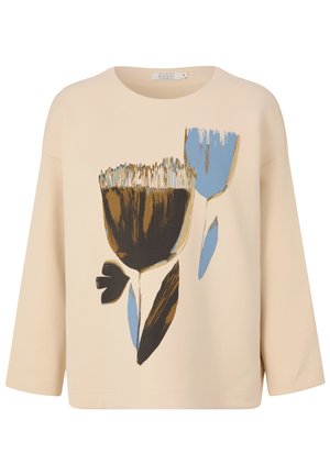 Beige bomuldsbluse med 3/4 ærmer, med et blomsterdesign i brun, blå og sort. Rund halsudskæring og løs pasform.