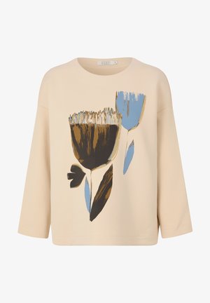 Top in cotone beige con maniche a 3/4, caratterizzato da un motivo floreale nei colori marrone, blu e nero. Collo tondo e vestibilità ampia.
