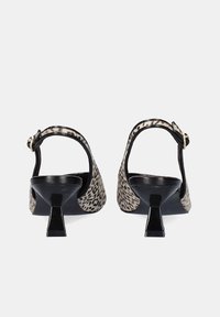 Par de zapatos de tacón kitten con talón abierto y parte superior de estampado de leopardo, vista desde atrás sobre un fondo blanco.