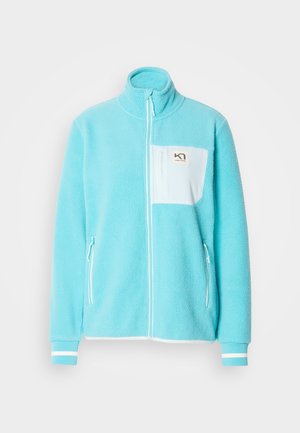 Fleece jack in lichtblauw met een ritssluiting aan de voorkant, een hoge kraag, een wit borstzakje en twee zijritszakken. De manchetten zijn voorzien van witte strepen.