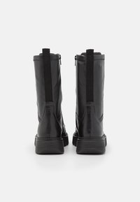 Botines de cuero negro con un acabado suave, paneles laterales elásticos y una suela de goma texturizada para mejorar el agarre. Altura de tacón suficiente.