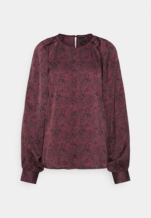 Blouse à manches longues en rose foncé avec un motif texturé de serpent, dotée d'un col rond et d'une fermeture éclair discrète au dos.