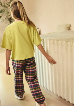 Helles gelbes kurzärmeliges Shirt mit lässiger Passform, kombiniert mit mehrfarbigen karierten Hosen in Pink-, Blau-, Grün- und Gelbtönen.