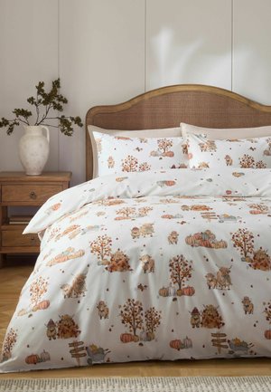 Bett mit herbstlich gestalteter weißer Bettwäsche mit Kürbissen, Bäumen mit Herbstlaub und kleinen Bauernhoftieren in einem gemütlichen Schlafzimmer.