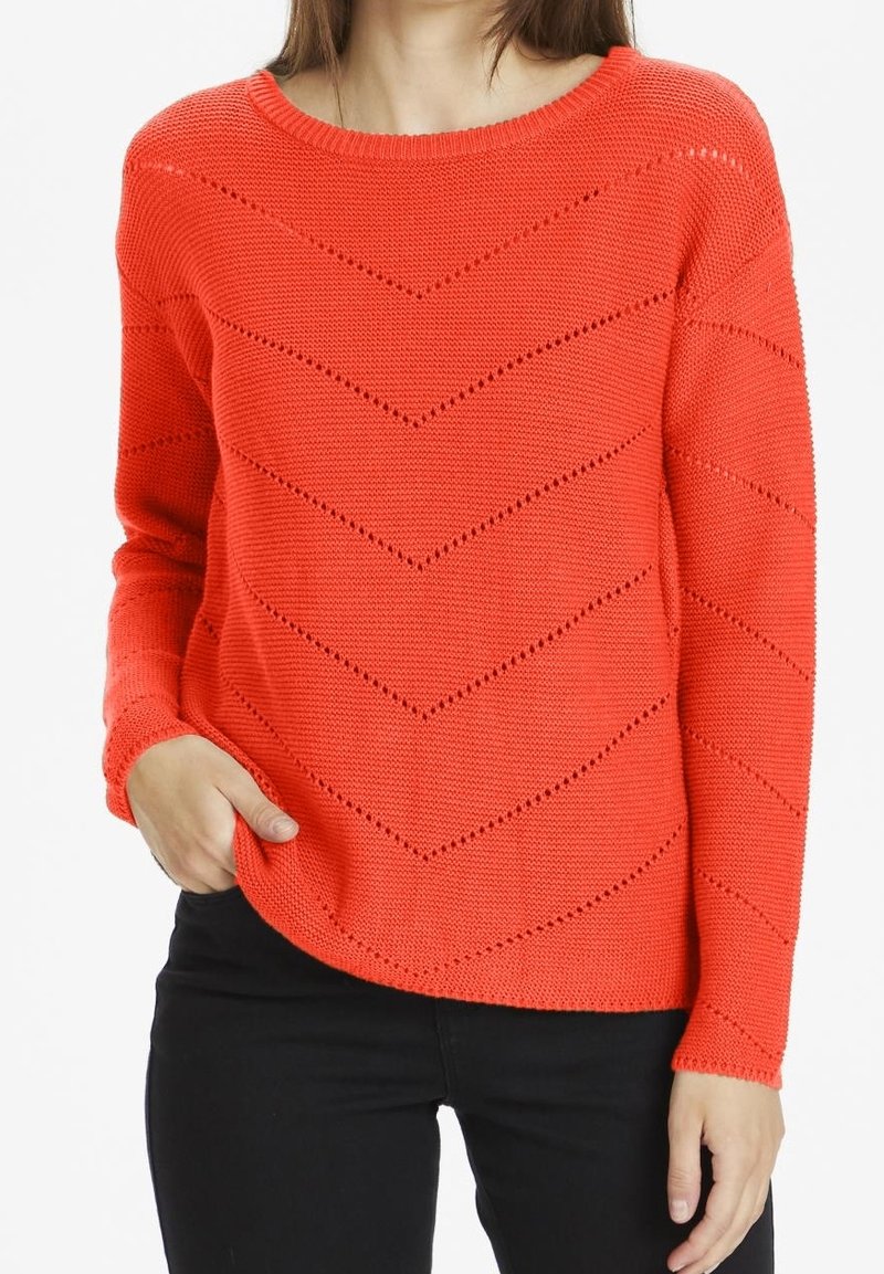 Lys orange sweater med rund halsudskæring, prydet med et chevron-mønster og struktureret strik. Lange ærmer og en afslappet pasform.