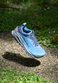 Chaussure de course en bleu clair et gris, dotée d'un dessus en mesh respirant, d'un col rembourré et d'une semelle texturée pour une meilleure adhérence.