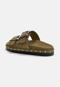 Olivgrüne Wildledersandalen mit zwei verstellbaren Riemen, silbernen Schnallen und metallischen Nietenakzenten entlang der schwarzen Gummisohle.
