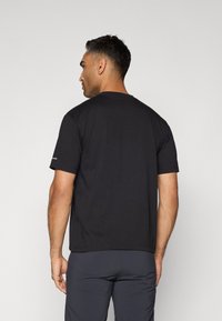 Black short-sleeve t-shirt with a round neckline, made of soft fabric. Features a logo on the sleeve and a relaxed fit.