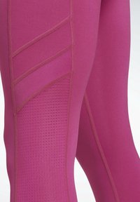 Leggings roses ajustés avec des panneaux en mesh texturé, des coutures contrastées et des éléments de design géométrique sur les côtés pour une meilleure respirabilité.