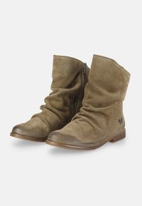 Par de botines de ante marrón, holgados, con cremalleras laterales y tacones de madera bajos, exhibidos sobre un fondo blanco.