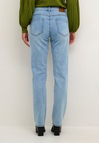Jeans de mezclilla azul claro con corte recto, que cuentan con dos bolsillos traseros y una etiqueta de cuero marrón en la cintura.