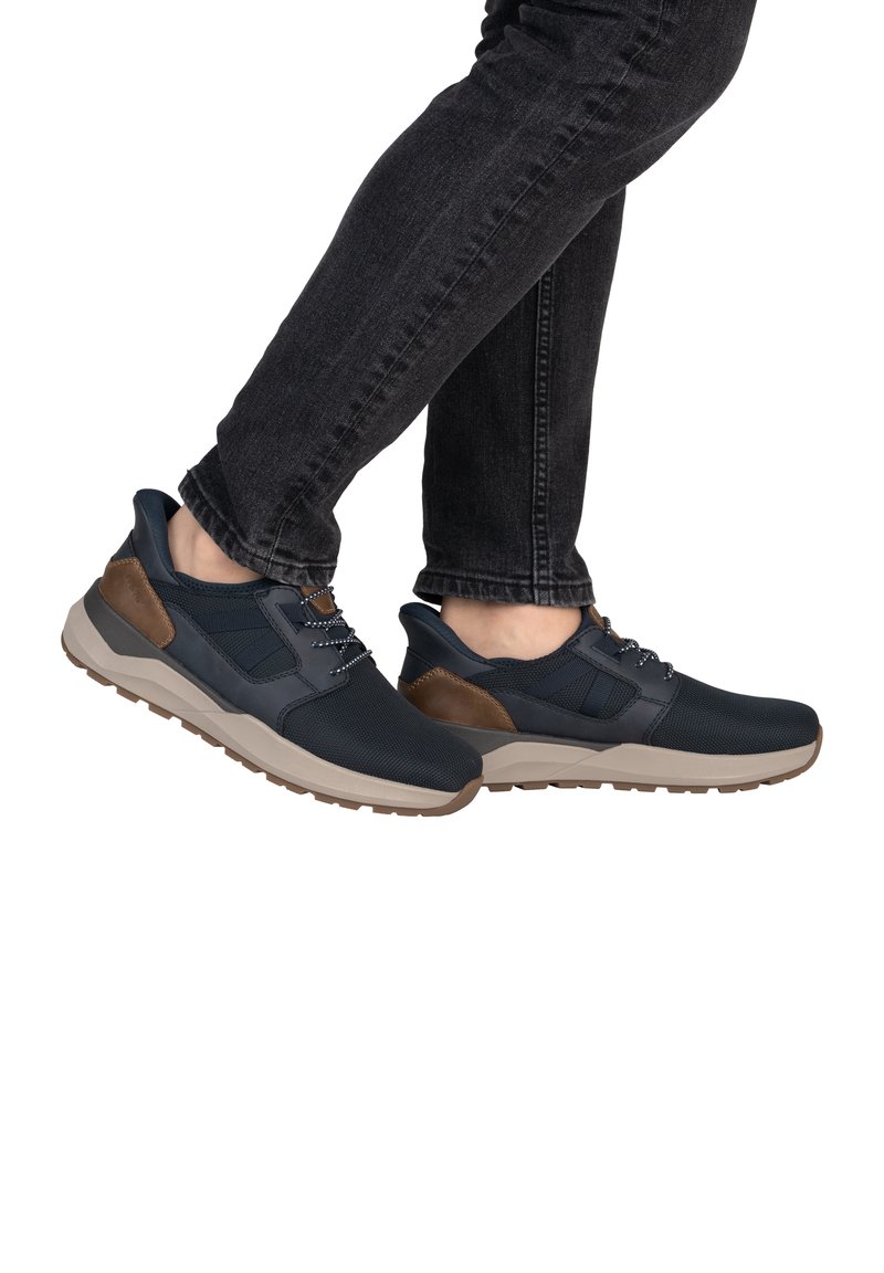 Baskets bleu marine avec un dessus texturé, accents marron sur le talon et une semelle gris clair. Comprend des lacets et un col rembourré pour un meilleur maintien.