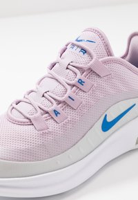 Ljuslila nät-sneakers med blå accenter, vadderad vit sula och integrerat snörsystem. Har "AIR" märkning på ovandelen.