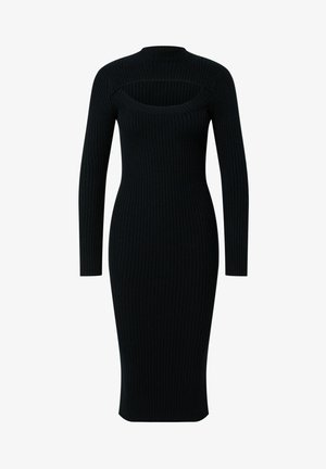 Femme portant une robe midi noire côtelée à manches longues et encolure découpée, associée à des bottines noires sur un sol gris.