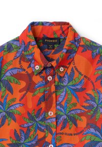 Camisa de manga corta de tela naranja con un patrón de hojas tropicales en verde y azul, con botones blancos y cuello.