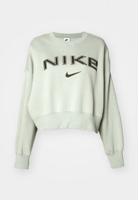 Ljusgrön kort sweatshirt i mjukt material med sänkta axlar, prydd med en stor svart "NIKE"-logotyp och en liten svart swoosh-emblem.