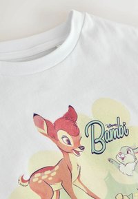 Valkoinen puuvillainen t-paita, jossa on värikäs Bambi-grafiikka peuran ja jäniksen kanssa. Kirkkaat värit, pehmeä texture, pyöreä kaula-aukko.