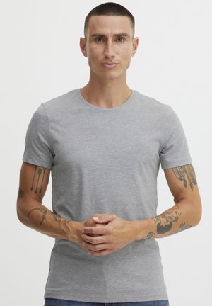Grå kortärmad t-shirt med rund halsringning, tillverkad i mjukt tyg. Har en figurnära design och slät textur, bärs med blå jeans.