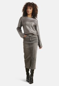 Grijze geribbelde lange mouwen trui met een ronde hals, gecombineerd met een grijze denim midi rok met een voorkantsplit en zwarte kniehoge laarzen.