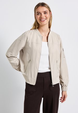 Ljust beige bomberjacka med frontdragkedja, sidofickor och ribbade muddarna. Gjord av ett mjukt material, har en minimalistisk design.
