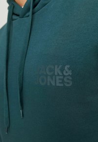Donkerblauwe hoodie van zachte stof, met een verstelbare capuchon. Opvallend reliëf logo "JACK & JONES" op de voorkant in een subtiele print.