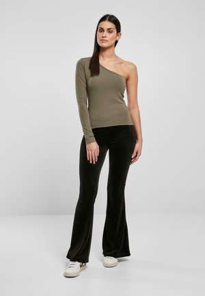 T-shirt à manches longues vert olive avec un décolleté asymétrique, associé à un pantalon noir évasé. Les tissus semblent lisses et extensibles.
