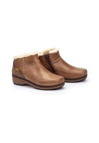 Botas de tobillo de cuero marrón con forro de piel sintética, cremallera lateral y suela de goma texturizada. Presentan costuras decorativas a lo largo de las costuras.