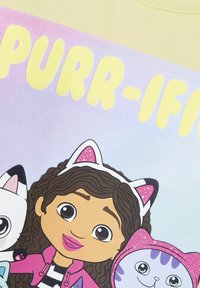 Katoenen T-shirt met een pastelgradiënt achtergrond. Bevat een cartoonfiguur die een kattenoor hoofdband draagt, omringd door cartoonkatten en vetgedrukte tekst.