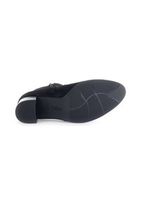 Zapato de ante negro con punta redonda, tacón bajo en bloque y suela de goma texturizada. Presenta un sutil logo grabado en la suela.