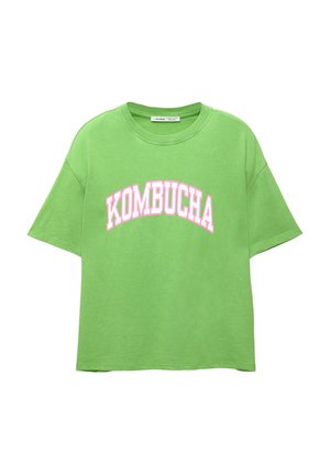 Grünes Baumwoll-T-Shirt mit lockerer Passform, Rundhalsausschnitt und kurzen Ärmeln. Mit "KOMBUCHA" in großen pinken Lettern auf der Vorderseite bedruckt.