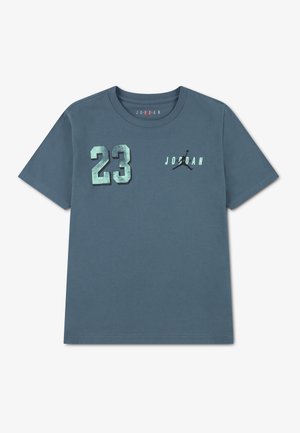 Niebieska koszulka z krótkim rękawem z metaliczną cyfrą 23 na lewej piersi oraz napisem "Jordan" i logo Jumpman na prawej piersi.