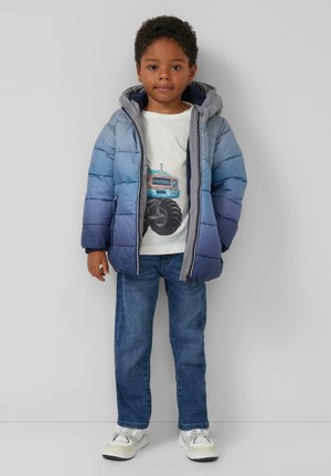 Gevoerde jas met een verloop in blauwe tinten, grijze capuchon en een rits aan de voorkant, gedragen over een lichte shirt met een vrachtwagenafbeelding en een spijkerbroek.