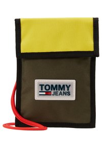Borsa di stoffa verde con patta gialla, bordatura nera, cordino rosso e un'etichetta con logo bianco. Forma rettangolare compatta.