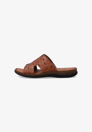 Brown slide sandal made of textured material featuring cutout design, cork midsole, and rubber outsole with grooves for traction.