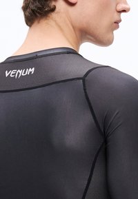 Czarna koszulka kompresyjna z teksturowanej tkaniny, o dopasowanym kroju i kontrastowych szwach. Marka "VENUM" widoczna jest na górnej części pleców.